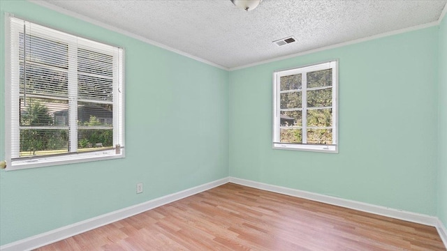 empty room featuring a textured ceiling, light hardwood / wood-style flooring, and a healthy amount of sunlight