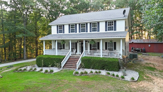 view of front of house with central air condition unit, covered porch, an outdoor structure, roof with shingles, and a front yard