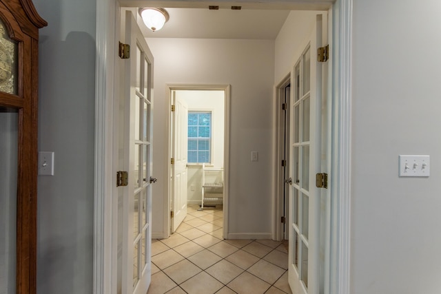 hallway featuring light tile patterned floors, french doors, and baseboards