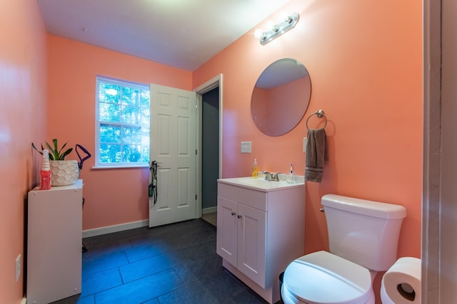 half bath with toilet, baseboards, and vanity