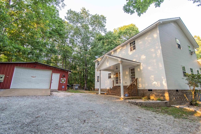 view of property exterior with an outbuilding, crawl space, a detached garage, and driveway