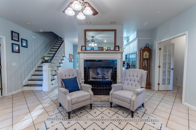 living room with light tile patterned floors, a fireplace, stairs, and a ceiling fan