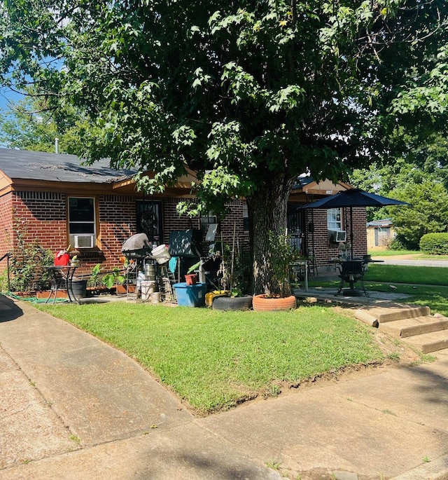 view of front of property with a front lawn, cooling unit, and brick siding