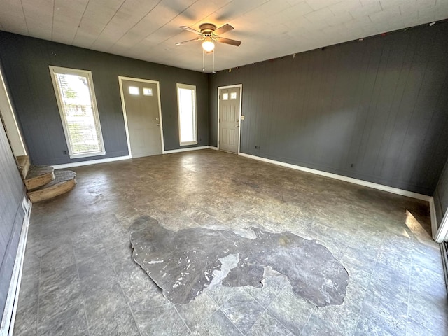 foyer featuring ceiling fan and wood walls