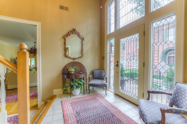 tiled foyer featuring baseboards, visible vents, a high ceiling, and stairway