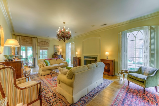 living room featuring ornamental molding, arched walkways, light wood-style floors, visible vents, and a notable chandelier