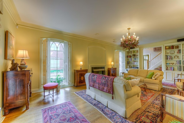 living area featuring wood finished floors, ornamental molding, and an inviting chandelier