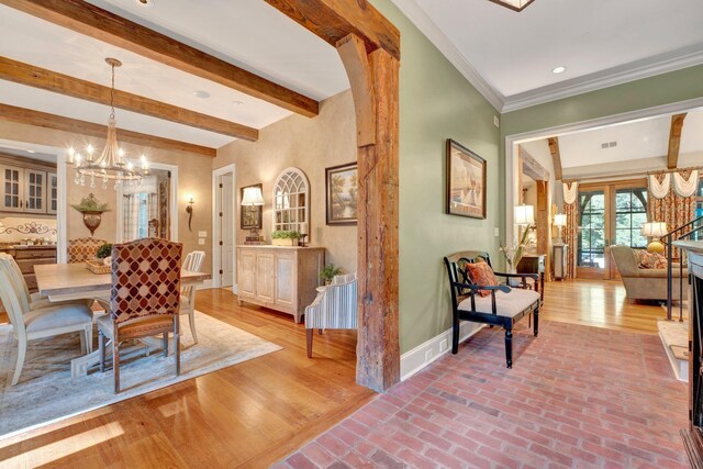 dining space featuring beam ceiling, hardwood / wood-style floors, an inviting chandelier, and crown molding