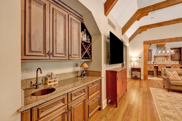 bar featuring light hardwood / wood-style floors, premium range hood, vaulted ceiling with beams, sink, and decorative light fixtures