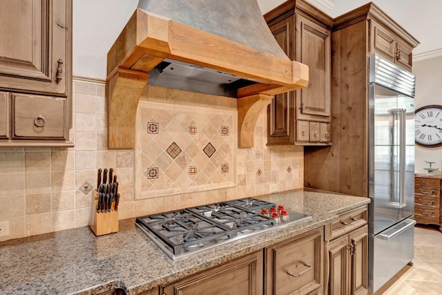 kitchen featuring custom exhaust hood, stainless steel appliances, light tile patterned floors, ornamental molding, and tasteful backsplash