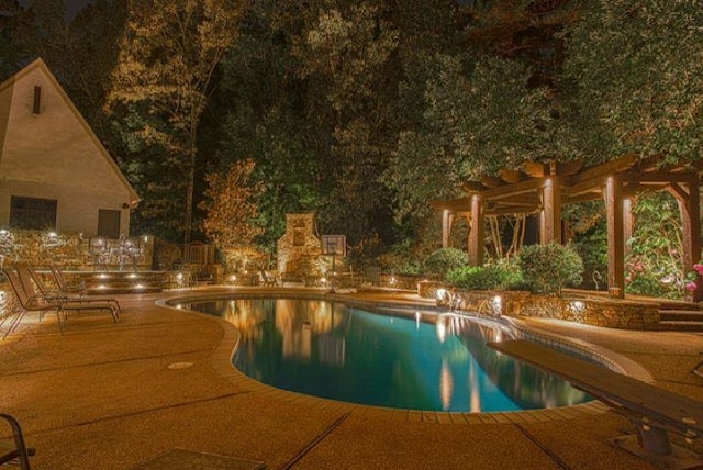 pool at night featuring a pergola and a patio area