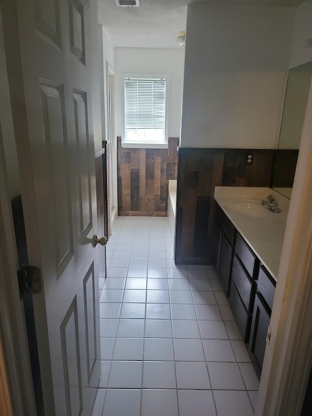 bathroom with tile patterned flooring, vanity, a bathtub, and wood walls