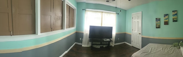 miscellaneous room featuring lofted ceiling, dark wood-type flooring, and a textured ceiling