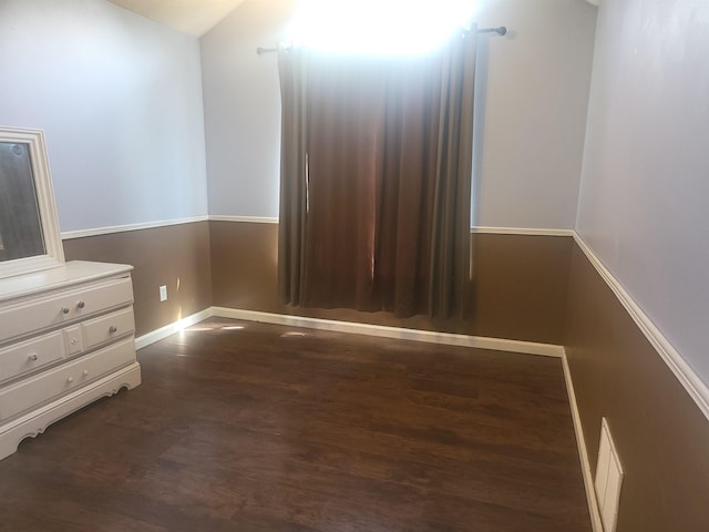 unfurnished bedroom with lofted ceiling and dark wood-type flooring