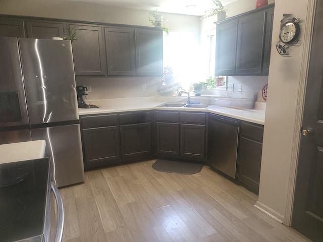 kitchen with dark brown cabinetry, stainless steel appliances, sink, and light hardwood / wood-style flooring