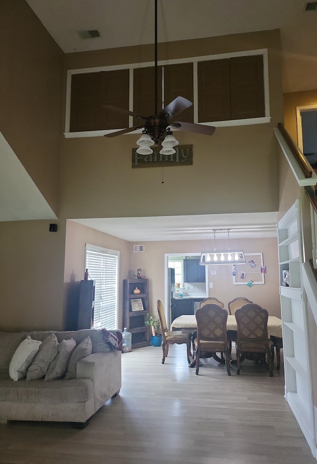 living room with wood-type flooring, a towering ceiling, and ceiling fan