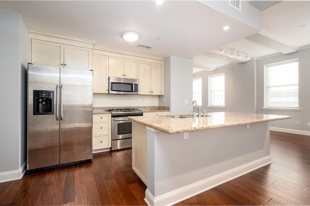 kitchen featuring stainless steel appliances, sink, light stone counters, and cream cabinetry