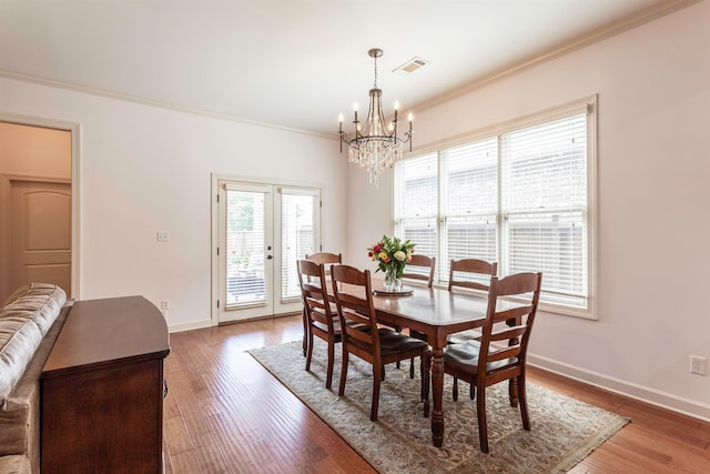 dining space with an inviting chandelier, crown molding, and hardwood / wood-style floors