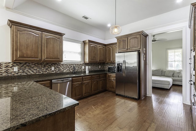 kitchen featuring dark brown cabinetry, stainless steel appliances, sink, and dark stone countertops