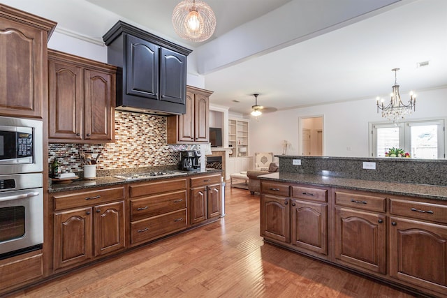 kitchen featuring hanging light fixtures, ornamental molding, stainless steel appliances, ceiling fan with notable chandelier, and light hardwood / wood-style floors