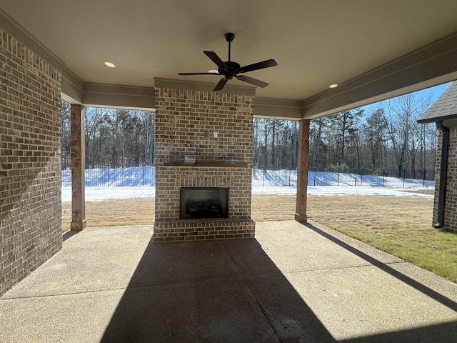 view of patio with an outdoor brick fireplace, ceiling fan, and fence