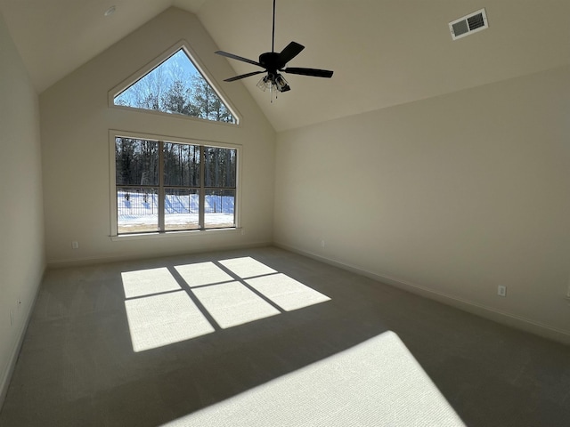 spare room with plenty of natural light, high vaulted ceiling, carpet, and visible vents