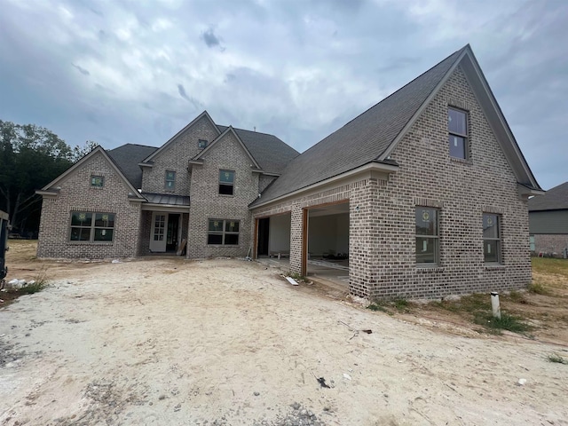 view of front of property with an attached garage, a shingled roof, and brick siding