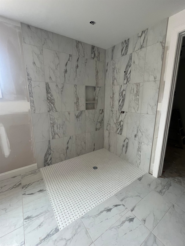 full bath with marble finish floor and a tile shower