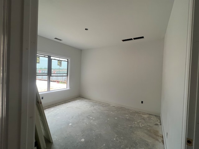 unfurnished room featuring visible vents, unfinished concrete flooring, and baseboards