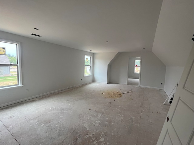 additional living space with vaulted ceiling, visible vents, plenty of natural light, and baseboards