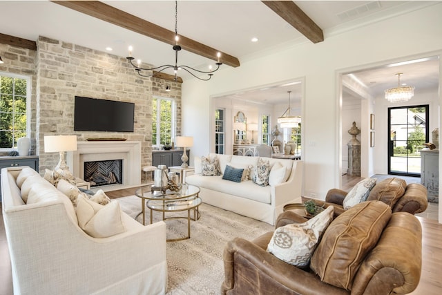 living room featuring beamed ceiling, a notable chandelier, a fireplace, and light wood-type flooring