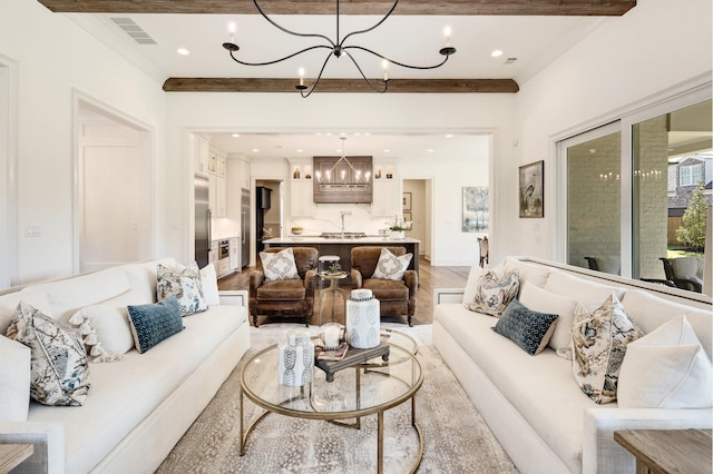 living room featuring ornamental molding, a chandelier, and light hardwood / wood-style floors