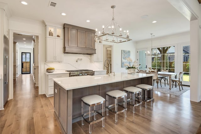 kitchen with hanging light fixtures, white cabinets, a notable chandelier, and a spacious island