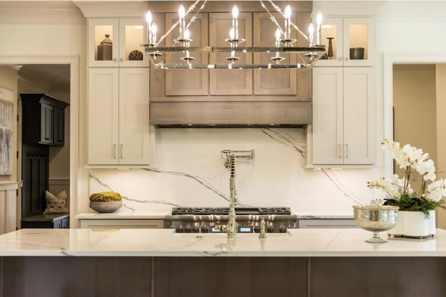 kitchen featuring backsplash, decorative light fixtures, light stone countertops, and white cabinets