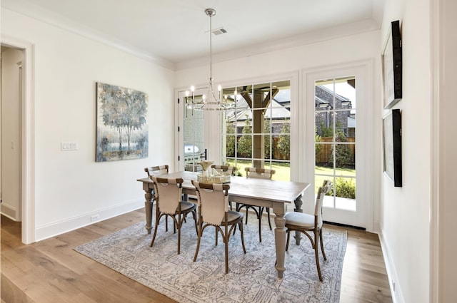 dining space featuring a notable chandelier, crown molding, and wood-type flooring