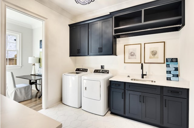 washroom featuring crown molding, cabinets, sink, and washing machine and clothes dryer