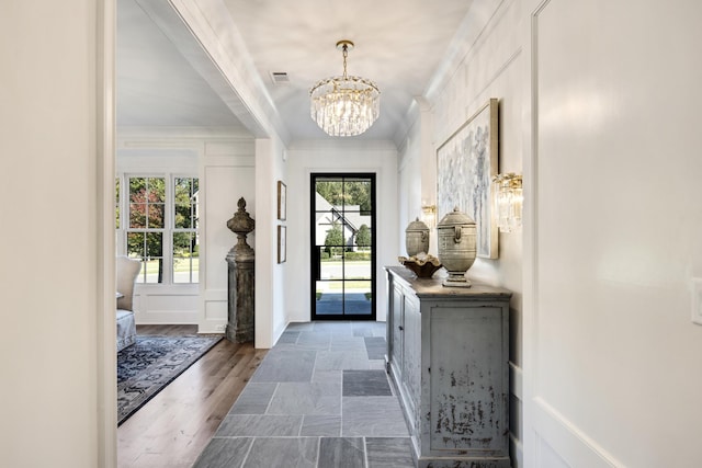 foyer entrance with ornamental molding, a healthy amount of sunlight, dark wood-type flooring, and a chandelier