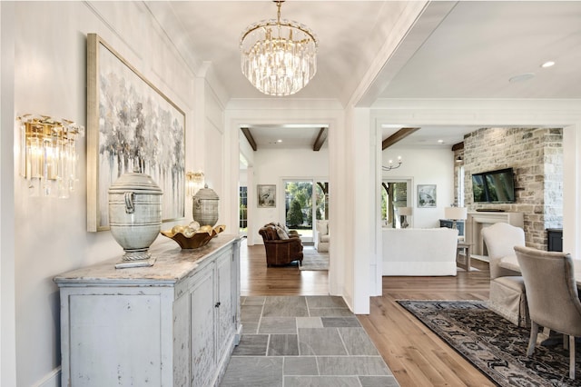 interior space featuring beam ceiling, crown molding, a notable chandelier, a fireplace, and hardwood / wood-style floors