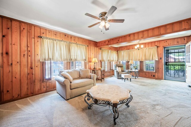 carpeted living room with ceiling fan and wooden walls