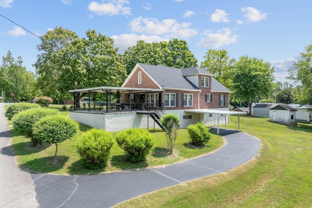 rear view of property with stairs, aphalt driveway, a lawn, and brick siding