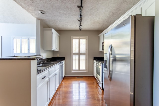 kitchen featuring appliances with stainless steel finishes, sink, white cabinets, and plenty of natural light