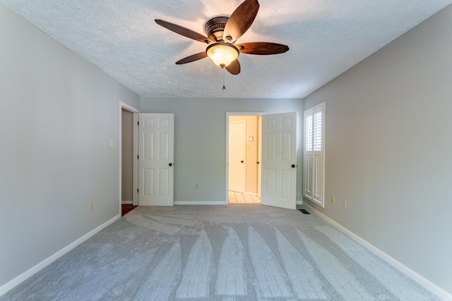 unfurnished bedroom featuring ceiling fan, light carpet, and a textured ceiling