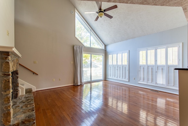 unfurnished living room with ceiling fan, wood-type flooring, high vaulted ceiling, and a textured ceiling