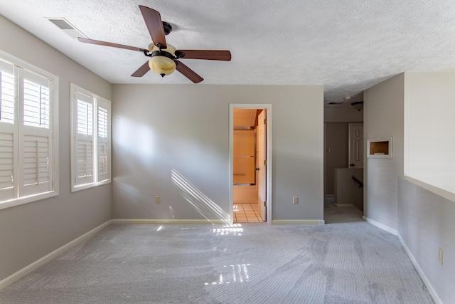 unfurnished room featuring ceiling fan, light carpet, and a textured ceiling