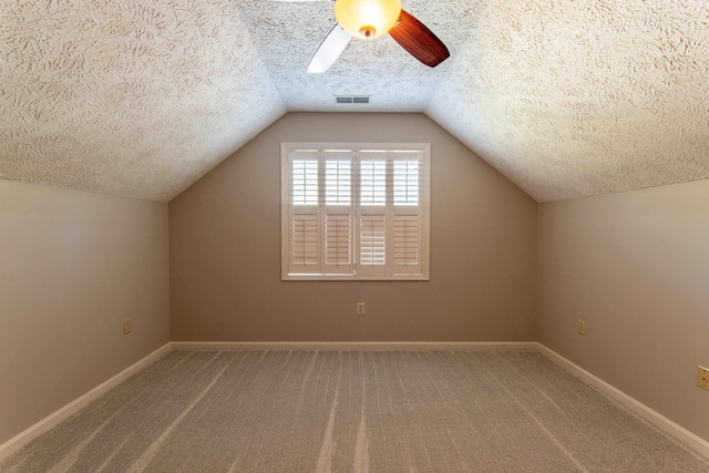 additional living space featuring ceiling fan, vaulted ceiling, carpet, and a textured ceiling