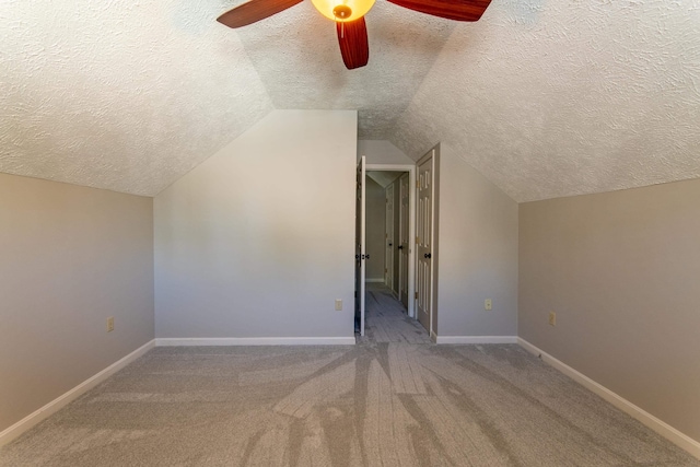 bonus room featuring ceiling fan, carpet floors, vaulted ceiling, and a textured ceiling