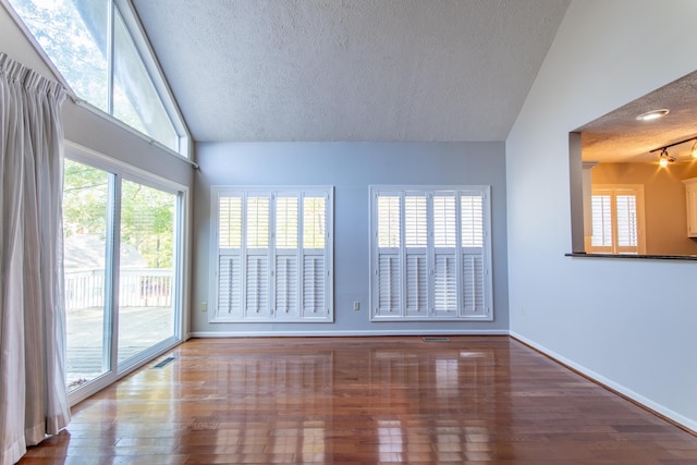 unfurnished room with wood-type flooring, lofted ceiling, and a textured ceiling