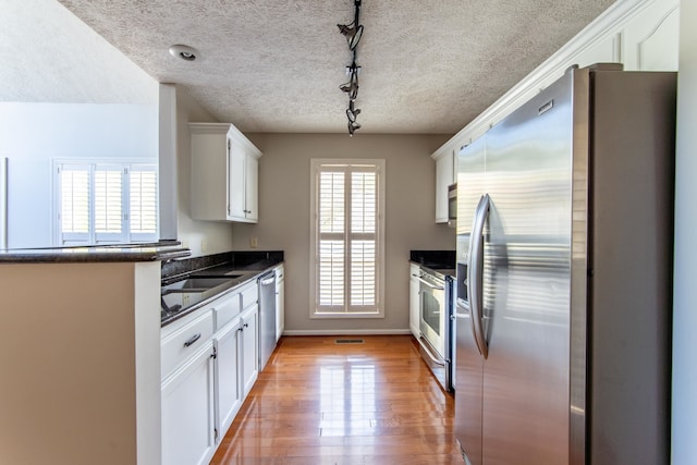 kitchen featuring stainless steel appliances, plenty of natural light, sink, and white cabinets