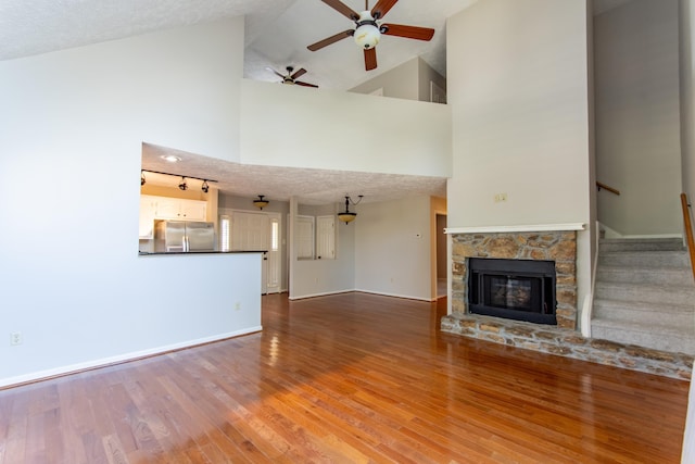 unfurnished living room with wood-type flooring, ceiling fan, a textured ceiling, and a fireplace