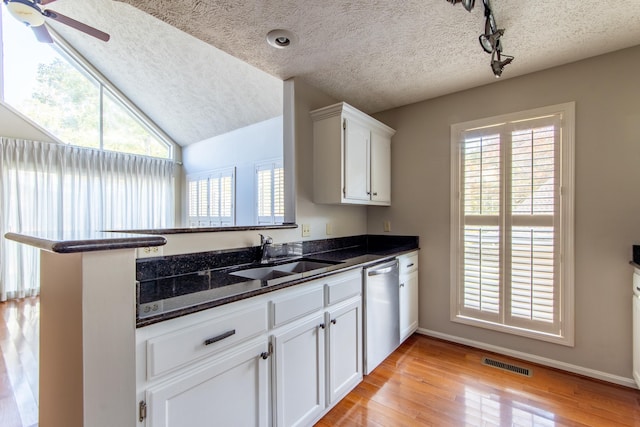 kitchen featuring sink, dishwasher, white cabinetry, kitchen peninsula, and dark stone counters